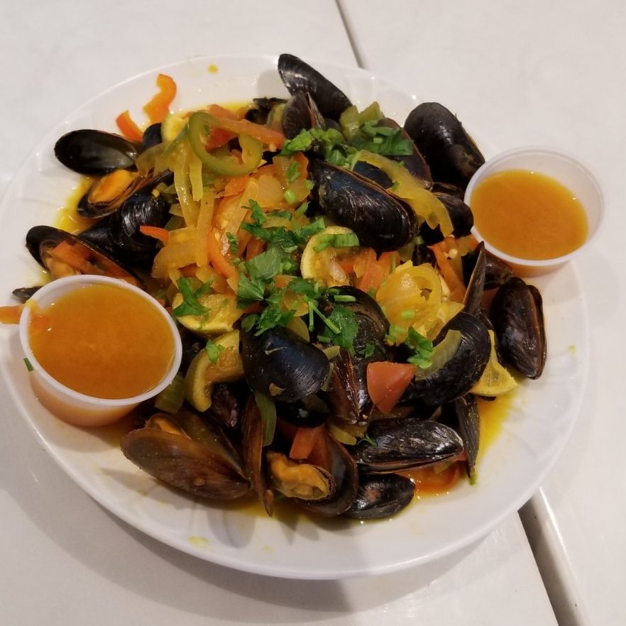 Plates of Mediterranean seafood on a simple table.